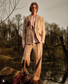 a man in a suit and tie standing on a log