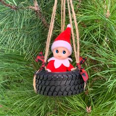 a christmas ornament hanging from a pine tree with a tire as a decoration