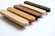 four wooden handles are lined up on a white surface, one is black and the other is brown