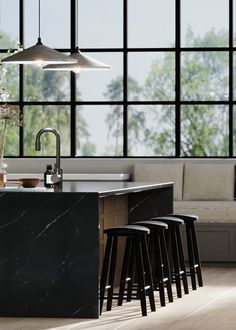 a kitchen island with stools next to it in front of a large window that looks out onto the outdoors