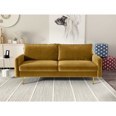 a yellow couch sitting on top of a rug in a living room next to a white wall