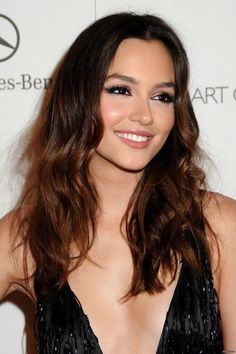 a woman with long brown hair wearing a black dress