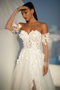 a woman in a wedding dress leaning against a wall with her hand on her head