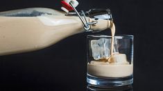 someone pouring milk into a glass with ice cubes