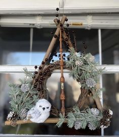 a wreath with an owl and pine cones hanging from it