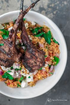 two lamb chops on top of rice in a bowl