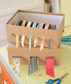 a cardboard box filled with lots of different colored tape and scissors on top of a table