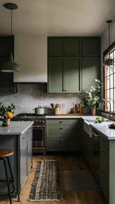 a kitchen with dark green cabinets and white counter tops, an area rug on the floor