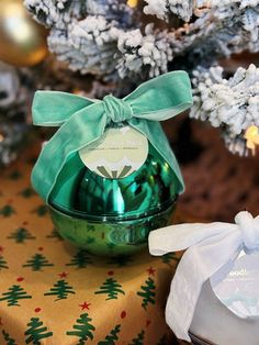 a green glass vase sitting on top of a table next to a present box and christmas tree