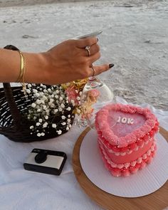 a heart shaped cake sitting on top of a table next to a basket with flowers