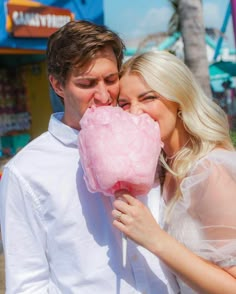 a man and woman kissing while holding a pink lollipop