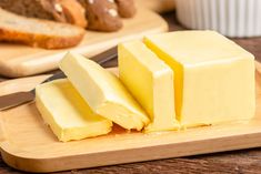 a block of butter sits on a cutting board next to other bread and pastries