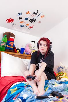 a woman sitting on top of a bed with headphones in her ears and holding a remote control