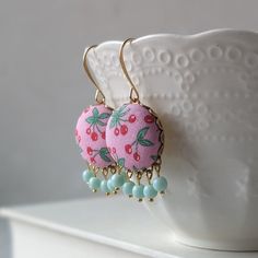 These earrings are perfect for anyone that loves vintage and whimsical themes - bright, fun, and full of playful charm, these earrings are handmade with vintage cherry fabric in shades of bright pink, green, and red.  Each earring has pastel mint glass beads that hang below, with long gold-plated ear wires at the top. The brass backings on the fabric give everything a finished look.  Full length - 1 3/4" (about 4.5 cm) Width - 3/4" (2 cm) All jewelry in my shop is crafted with care in Denton, TX Handmade Retro Dangle Jewelry, Retro Handmade Dangle Jewelry, Whimsical Pink Earrings For Gift, Retro Dangle Jewelry As Gift, Retro Dangle Jewelry As A Gift, Vintage Dangle Clip-on Earrings For Gift, Handmade Red Plug Earrings As Gift, Playful Red Drop Earrings, Handmade Retro Dangle Earrings