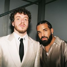 two men standing next to each other in suits