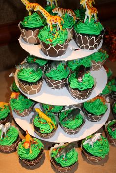 cupcakes with green frosting and giraffe decorations on top are arranged in the shape of a tower