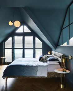 an attic bedroom with blue walls and wooden flooring, large bed in the center