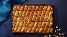 a pan filled with food sitting on top of a blue table cloth next to nuts