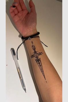 a person's arm with a tattoo on it and a pen next to it