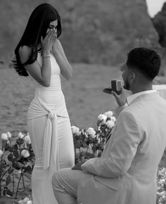 a man kneeling down next to a woman holding a camera in front of her face