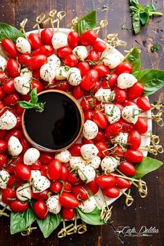 a platter filled with tomatoes and mozzarella on skewers, garnished with basil leaves