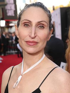 a woman with grey hair wearing a black dress and white collared neck tie on the red carpet