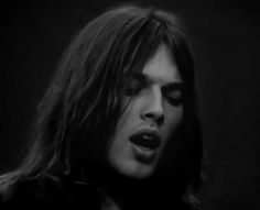 a man with long hair is singing into a microphone