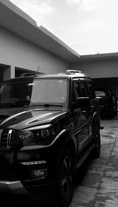 black and white photograph of cars parked in front of a building