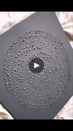 a black object with water drops on it and a white sheet in the foreground