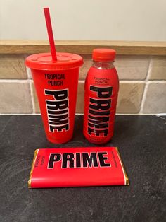 two plastic cups with straws next to each other on top of a black counter