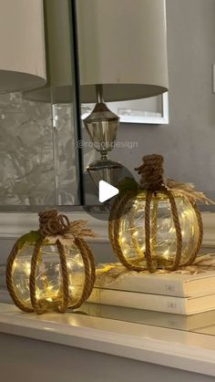 two glass pumpkins sitting on top of a table next to a lamp and books