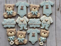 baby shower cookies with teddy bears and onesuits on wooden table next to wall