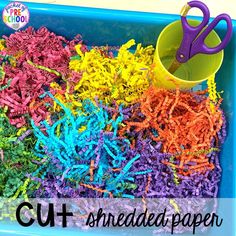 colorful shredded paper in a blue bin with scissors and sprinkles on it