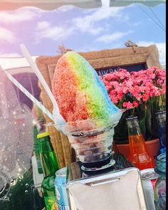 an ice cream sundae is sitting on a table with flowers in the back ground