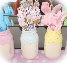 three mason jars filled with pink, blue and yellow paper straws on top of a table