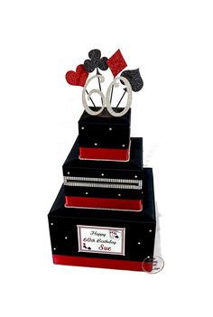 a three tiered black and red wedding cake with hearts on the top is decorated with silver scissors