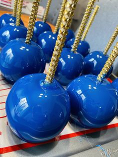 several blue balls with gold spikes on them sitting on a table in front of a ruler