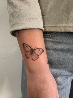 a woman's arm with a small butterfly tattoo on the left side of her arm