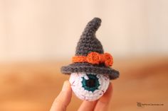 a hand holding an eyeball with a hat on it