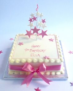 a birthday cake with pink ribbon and stars on it