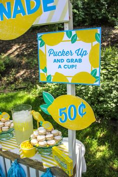 a table topped with cupcakes and lemonade next to a sign that says made