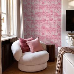 a living room with pink wallpaper and white furniture