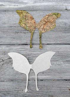 two butterflies made out of paper sitting on top of a wooden table