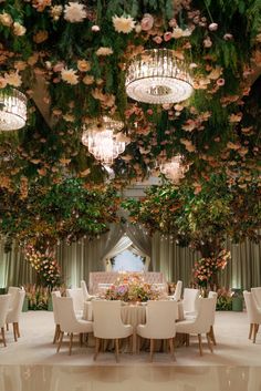 an elaborately decorated banquet room with chandeliers and flowers hanging from the ceiling