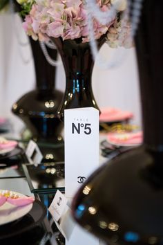 the table is set up with black vases filled with flowers and plates on it