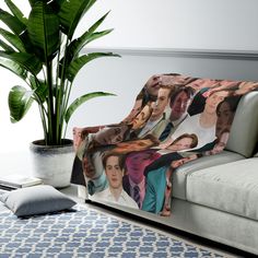 a couch with a blanket on top of it next to a potted plant