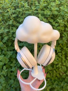 there is a cloud shaped headphone holder in the palm of someone's hand