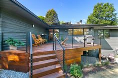 a house that has some stairs leading up to the front door and steps down to the deck