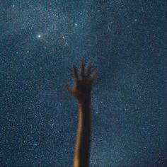 a person reaching up into the sky with their hands in the air and stars above them