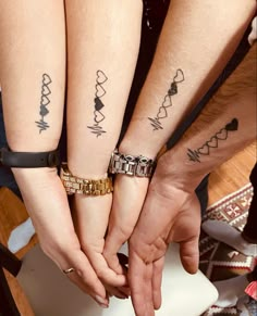 three people holding hands with tattoos on their arms